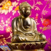Brass Buddha figurine on floral fabric.