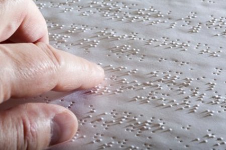 A finger reading braille writing on a page.