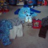 Flanel pajamas, rain coat, two pairs pants with matching shirts, another shirt, and a pair of shoes in toddler sizes as well as a pair of adult sneakers and a butterfly decoration.