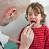 A doctor examining a child with a sore throat.