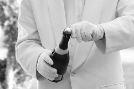 Man in White Gloves and Suit Opening a Bottle of Champagne