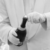Man in White Gloves and Suit Opening a Bottle of Champagne
