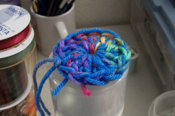 Crochet pin cushion on spray paint can lid, closeup.