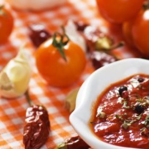 Bowl of salsa with ingredients in background.