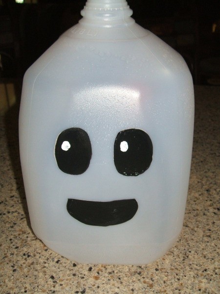 Finished milk jug ghost. Black eyes and black mouth painted on white milk jug.