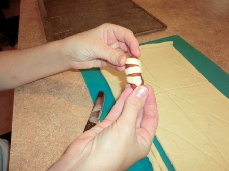 Wrapping strips of croissant dough around sausages.