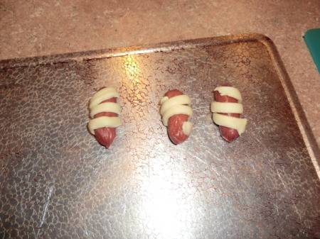 Placing wrapped sausages on a baking sheet.