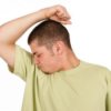 Man in Green Shirt Smelling His Underarm