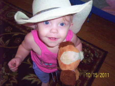 A toddler with a cowboy hat and a toy hobby horse.