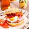 Ham, bacon, and egg sandwich on a crusty bun.