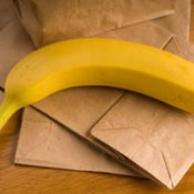 Photo of two bananas and a brown paper bags.