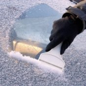 Removing Ice from Your Windshield, Gloved hand scraping icy windshield.