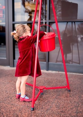 Girl in a red coat giving to the Salvation Army.