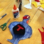 Turkey cutout, colored in blue with cape and eye mask placed on top ready to be glued.
