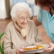 An elderly woman being served a meal.