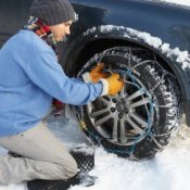 Preparing Your Car for Winter, Young man putting snow chains on his car tire