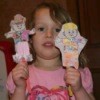 A girl holding two paper dolls.