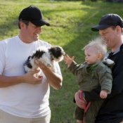 A man introducing his dog to a father and child.