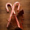 Two crossed candy canes and a tree shaped cookie cutter.