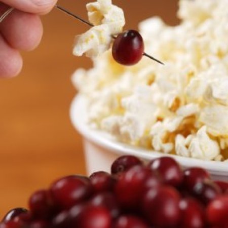 Someone making a cranberry and popcorn garland.