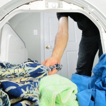 Removing Melted Crayon from Dried Clothes, Man removing clothes from the dryer.