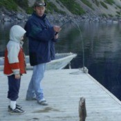 Man and a boy catching a fish on a dock.