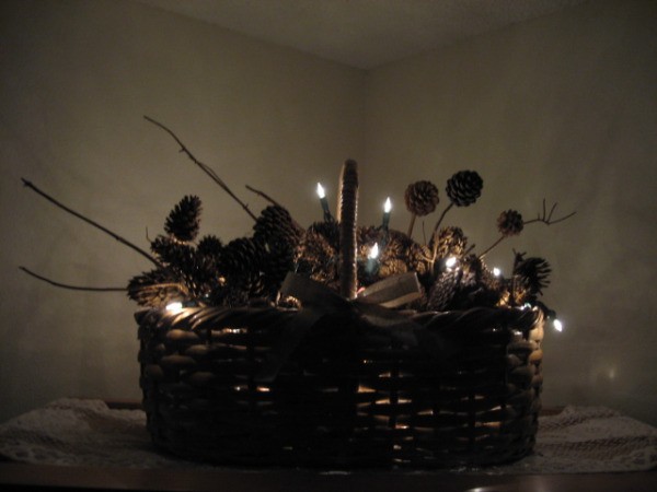 Lighted holiday basket with pinecones and twigs