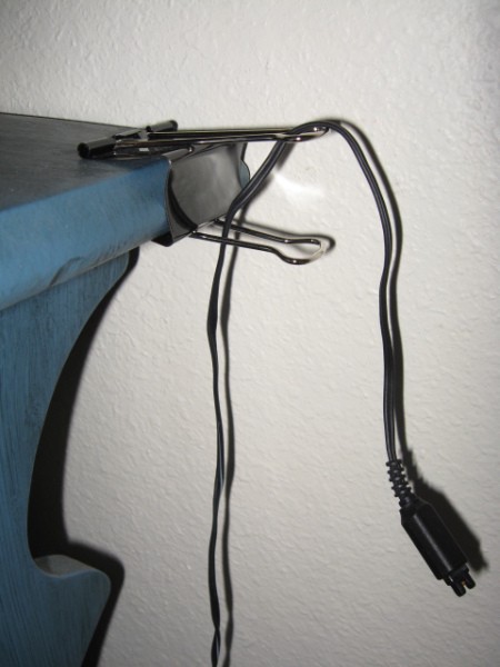 Large paper clip attached to table for cord.