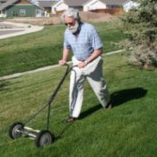 Environmentally Friendly Lawn Mowers. A man pushing a reel mower.