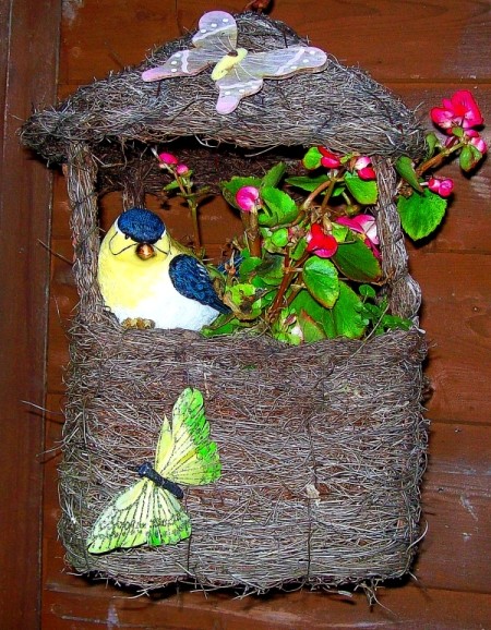 A garden decoration with a blooming plant, artificial butterflies and a bird.