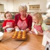 Grandmother showing her granddaughters how to make muffins.