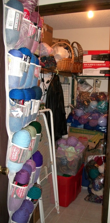 Closet after reorganizing.  Shoe rack on back of door holds yarn, boxes are organized, more yarn and items are stored in clear plastic bins and large clear bags