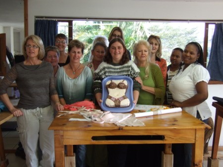 Ladies sewing group with a torso cake in bra and panties.
