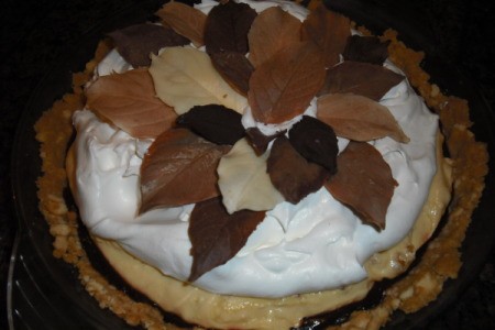 Whole pie with chocolate, peanut butter, and whipped cream layers topped with dark and white choclate leaves