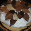 Whole pie with chocolate, peanut butter, and whipped cream layers topped with dark and white choclate leaves