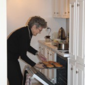 Author's mother removing baked goods from the oven.