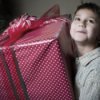 A boy holding a large wrapped Christmas present.