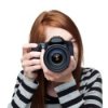 A girl in a striped shirt holding a camera to her eye.