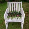 White chair turned into a planter with flowers in it.