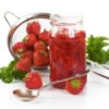 Fresh strawberries in a jar with a colander in the background.