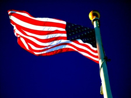 American flag unfurled against royal blue sky.