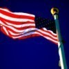 American flag unfurled against royal blue sky.