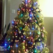 Artificial Christmas tree with lights, decorations, and large gold ribbon bows.