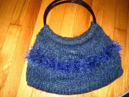 A purse that has been knitted from blue yarn.