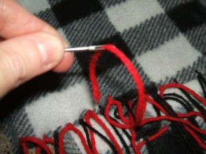Using a large needle to add yarn fringe.