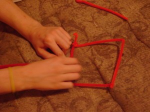 Child's hands shaping pipe cleaners.
