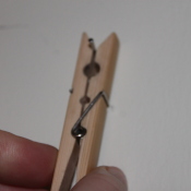 Closeup picture of hand holding spring type clothespin against a white background