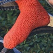 A homemade crocheted sock in an orange-red color.