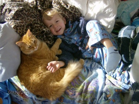 A boy lying with his orange cat, Tigger.