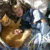 A boy lying with his orange cat, Tigger.